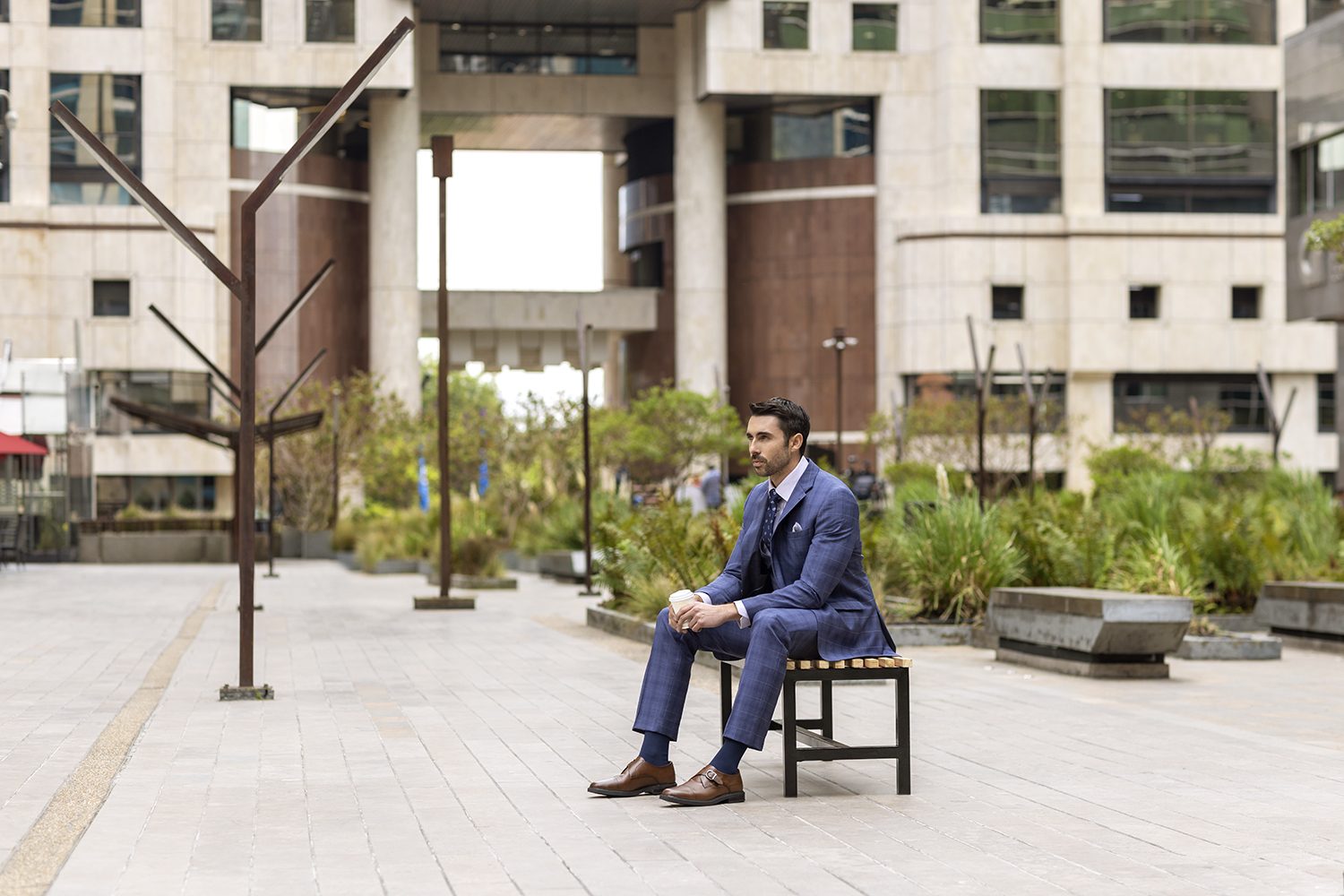 A man in a suit sits on a bench in a Bogotá plaza