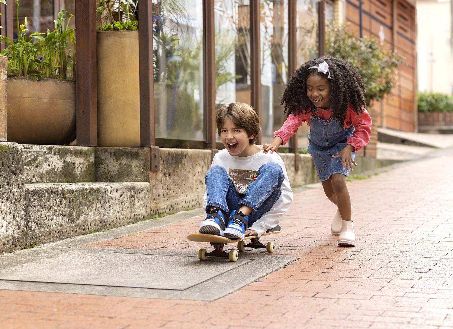 Two children play on a skateboard in the old town