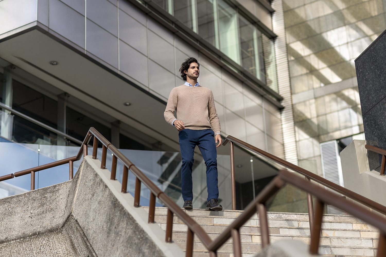 A man on a staircase beside a glass facade