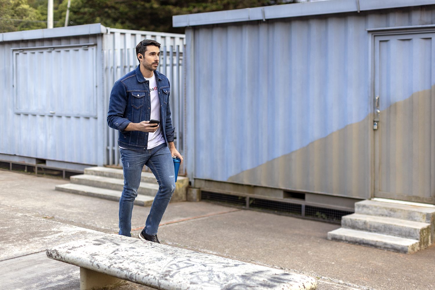 A man walks past a blue wall with a coffee