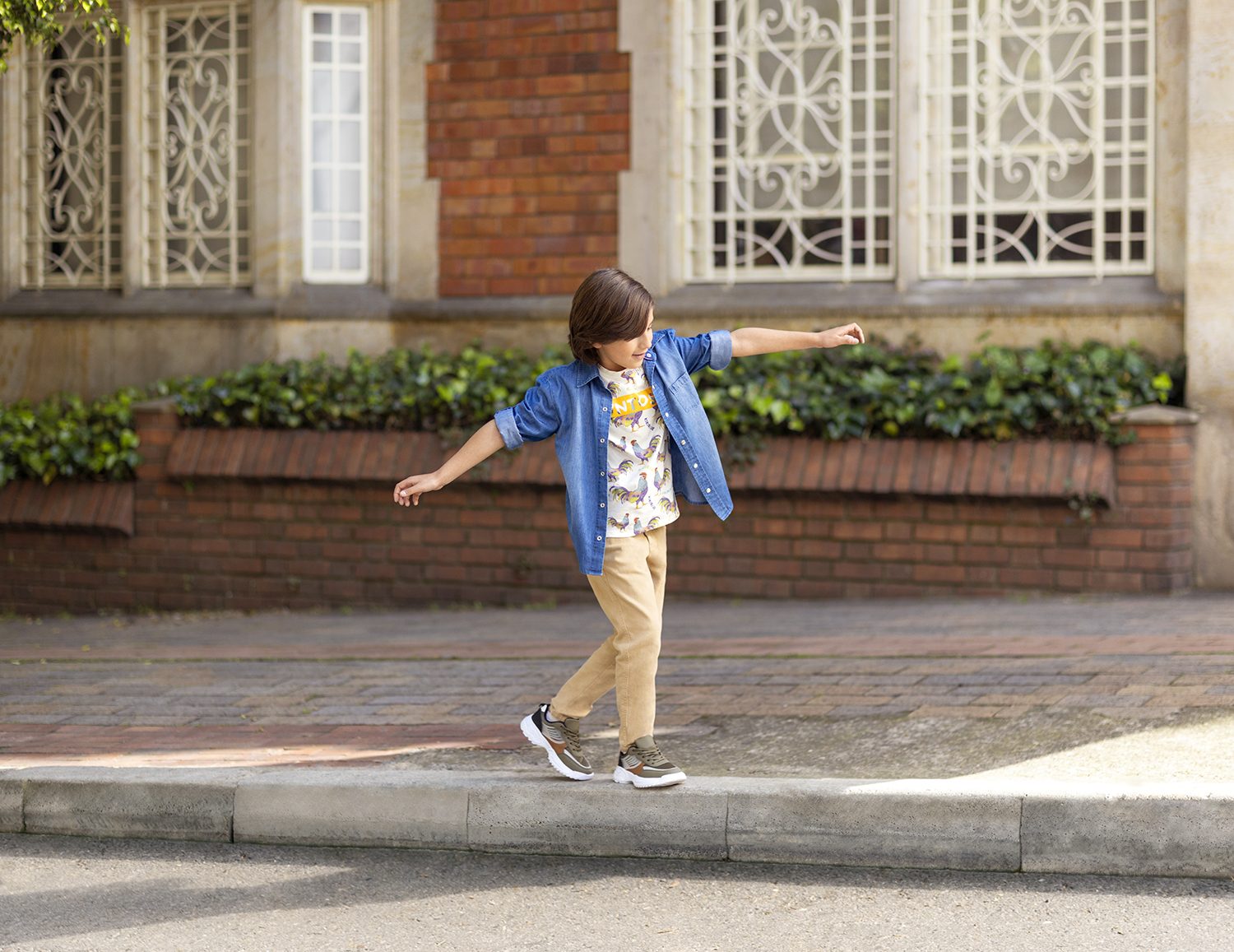 A boy skateboards past a brick facade