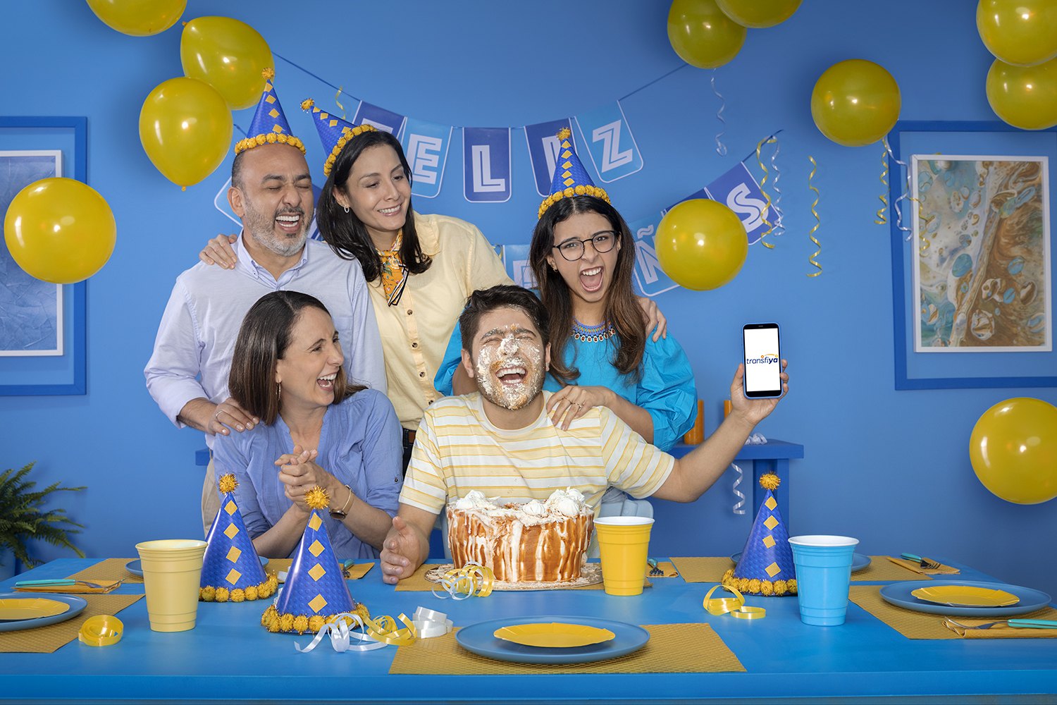A family around a birthday table under yellow balloons and blue bunting