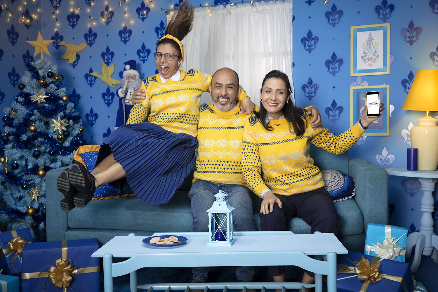 A family in a blue living room at Christmas, yellow knitwear and a decorated tree