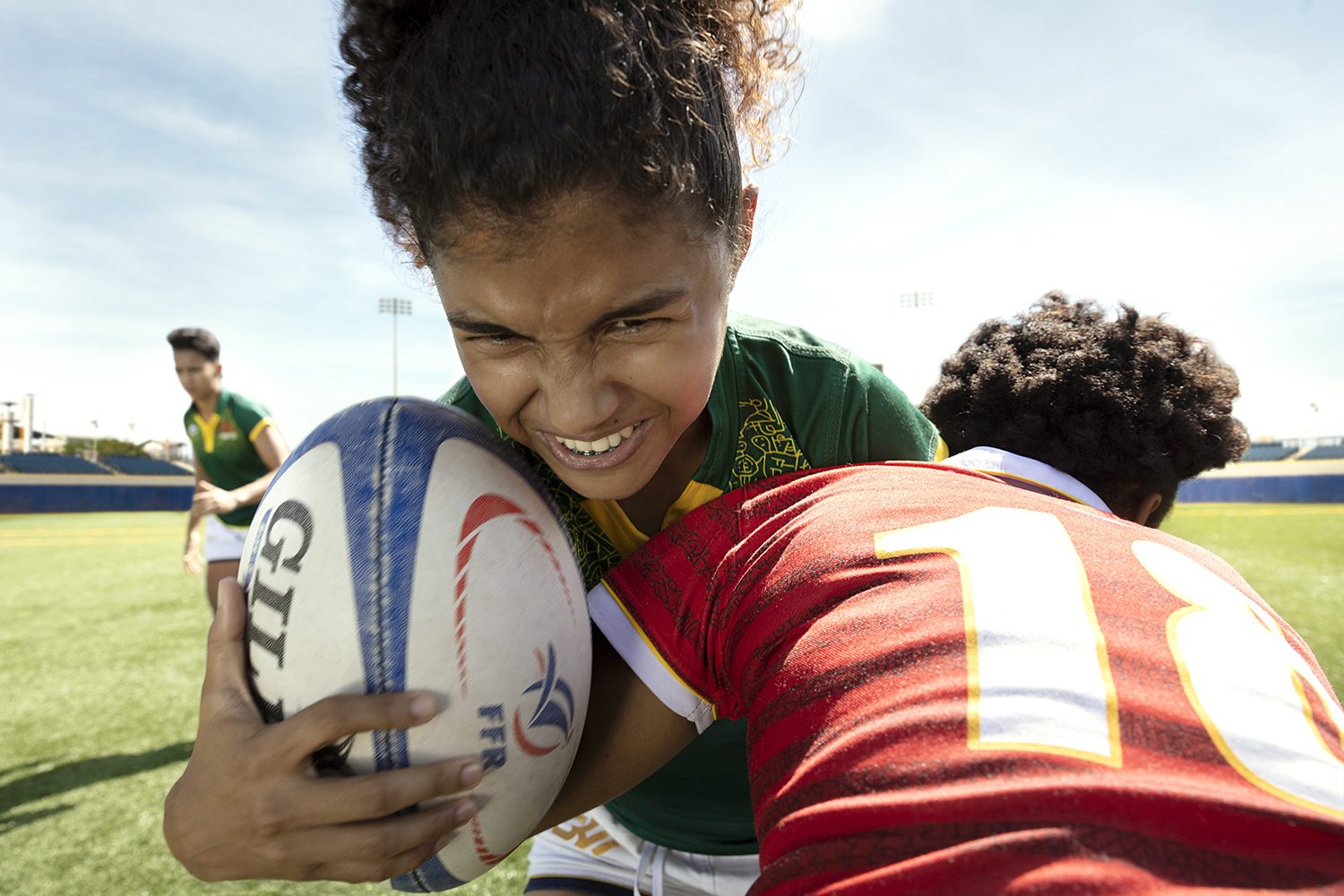 A rugby player braces for a tackle, ball held tight