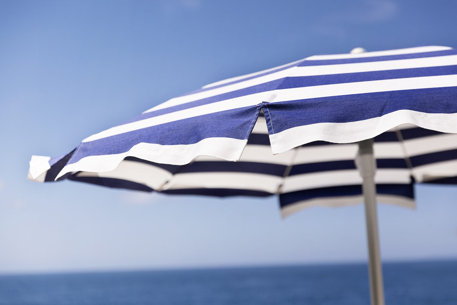 A single blue-and-white striped umbrella on a Capri beach