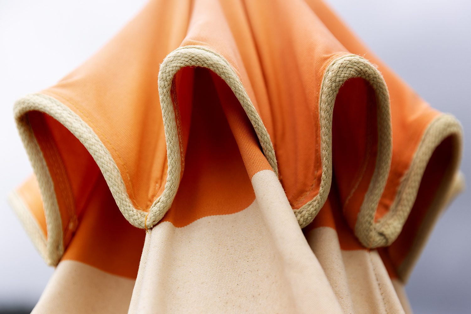 Orange beach umbrella seen from above on the sand