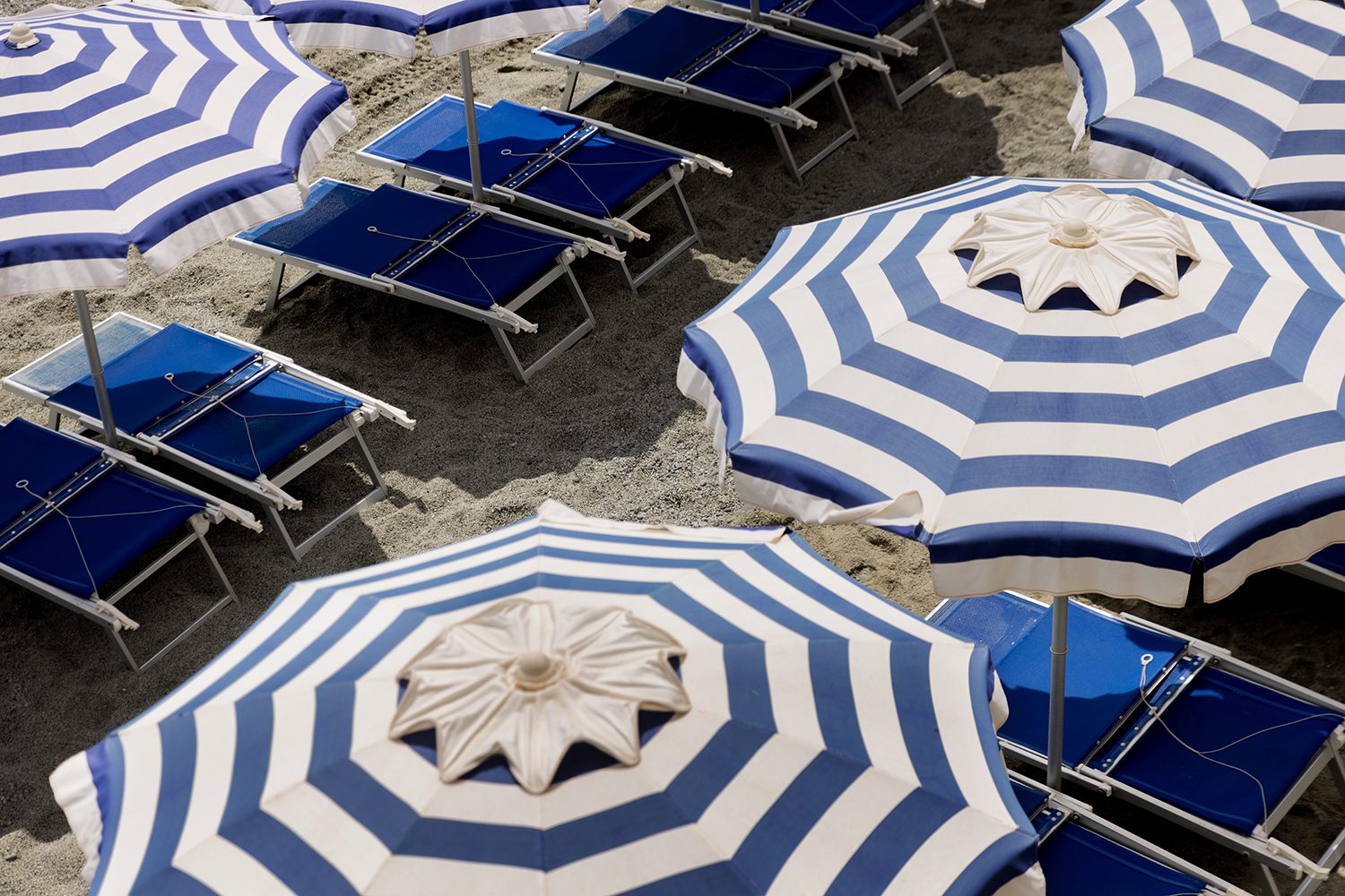 Rows of blue umbrellas lined along the shore in Capri