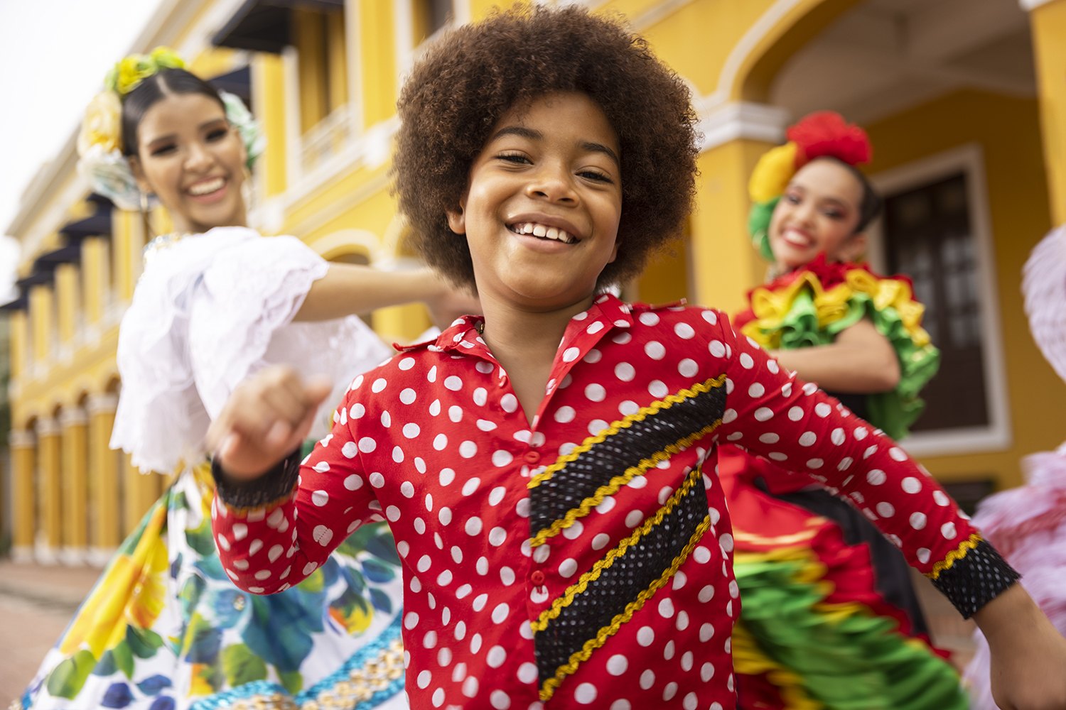 Children in carnival dress reaching towards the camera, arms out