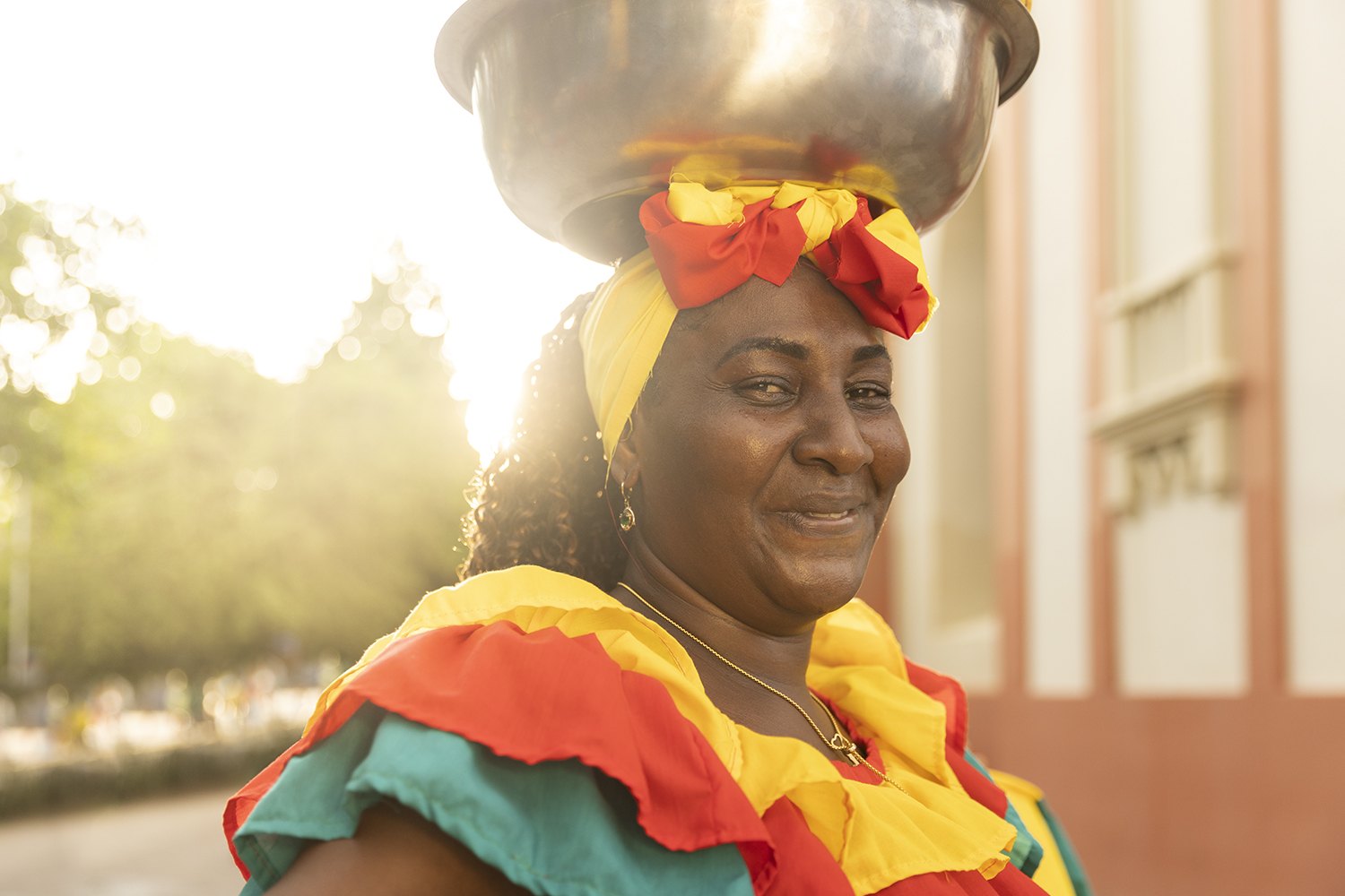 Portrait of a fruit seller with the sun flaring behind her headwrap