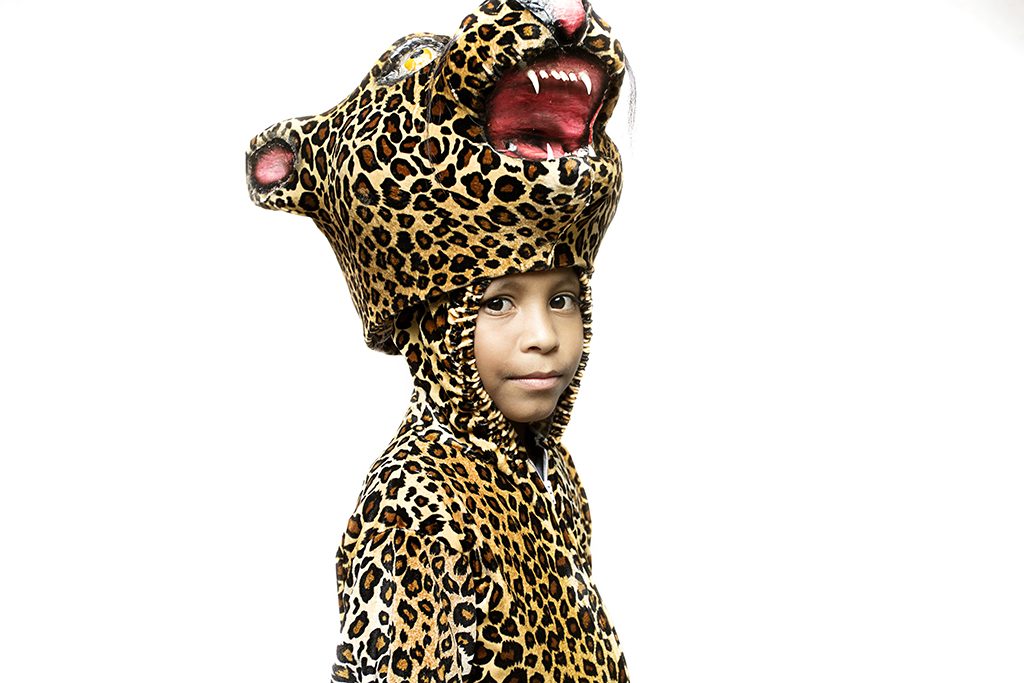 A child in a leopard costume against a white wall