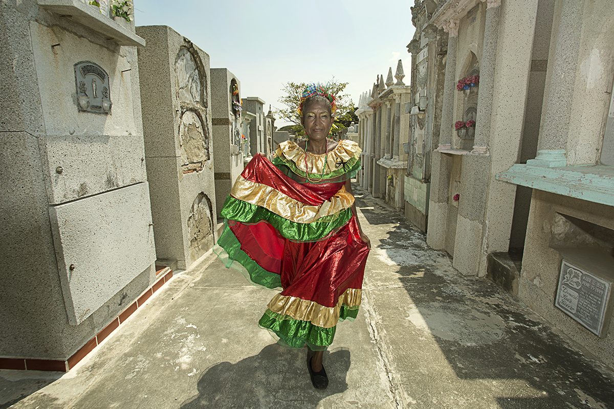 A costumed dancer moves through a narrow street