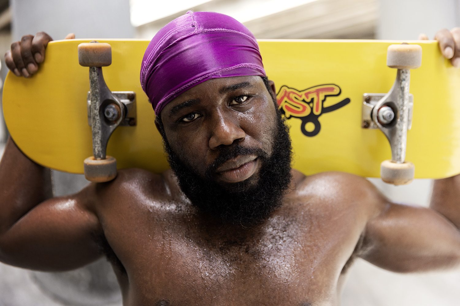 A skater's portrait, deck held behind his shoulders