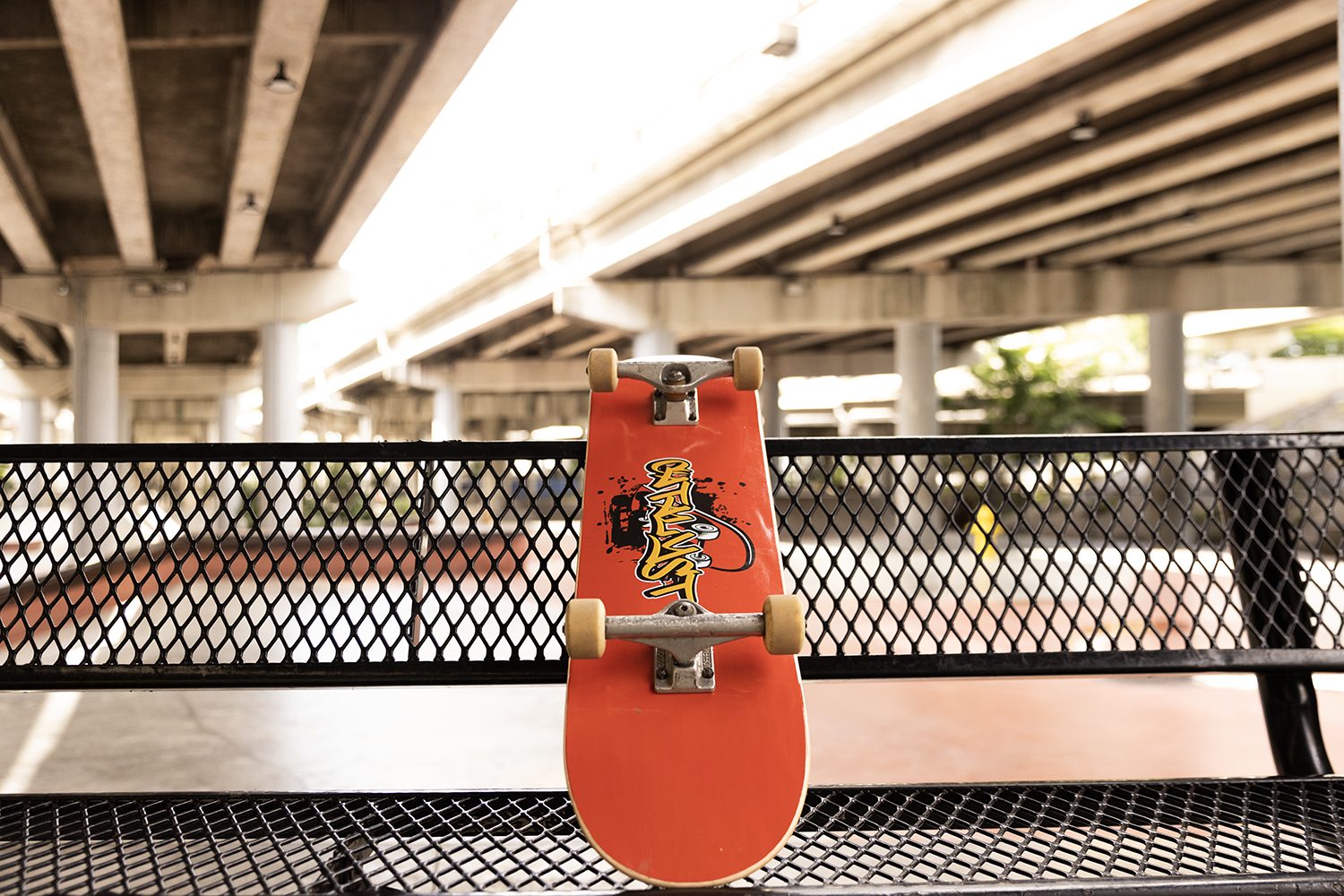 A red board leans on a ledge under the highway