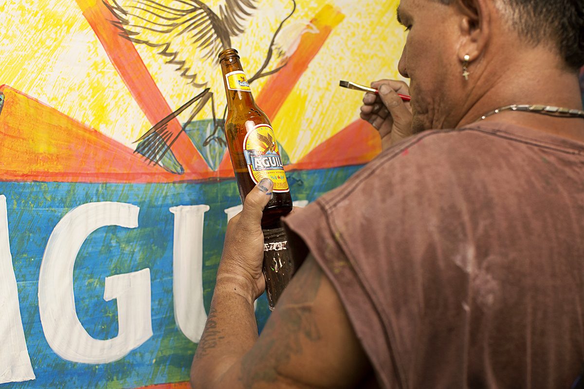 An artist paints an Águila mural on a wall