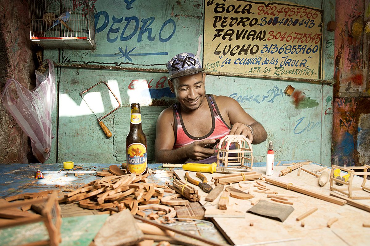 A woman holds a cold Águila beer at the beach