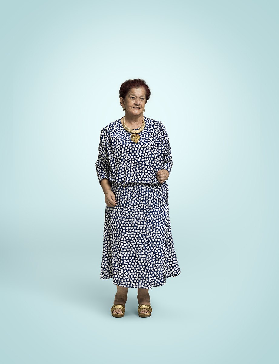 A woman in a printed dress standing alone on the seamless, hands easy at her sides