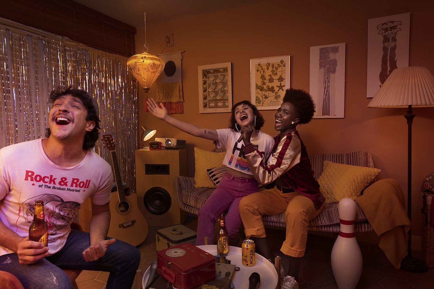 Three friends singing in a warm living room with a paper lantern, guitar and record player