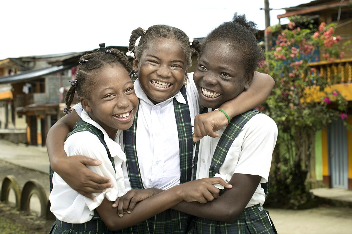 Schoolchildren embrace and smile for the camera in Lloró