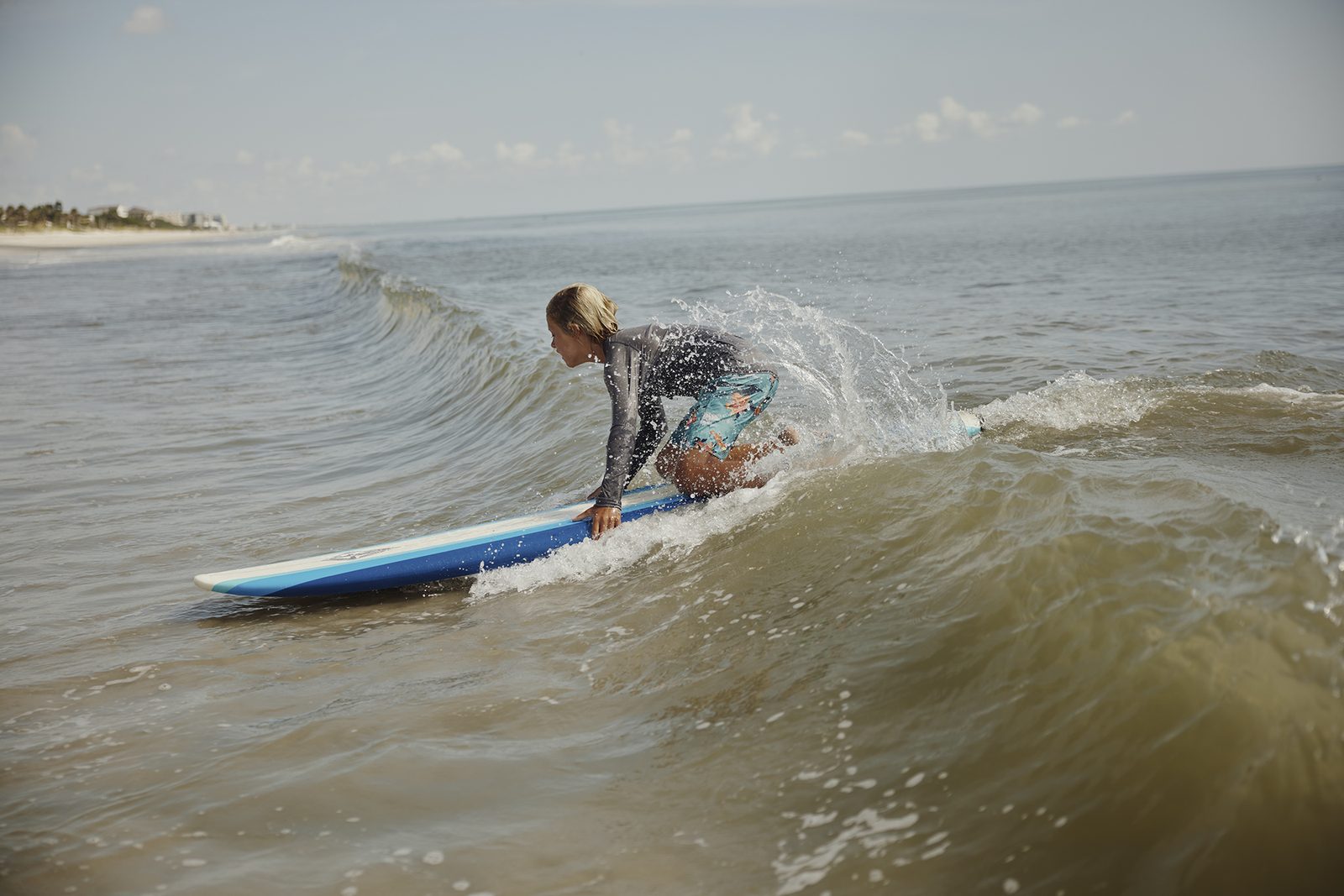 A young surfer rides a small wave