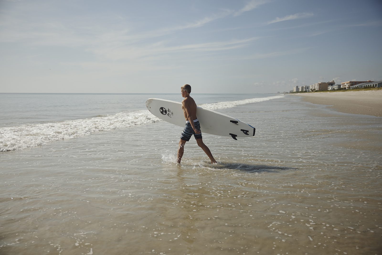 A surfer walks out of the shallows with a board