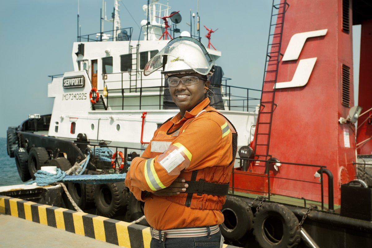 A crew member aboard a red working tug at the dock