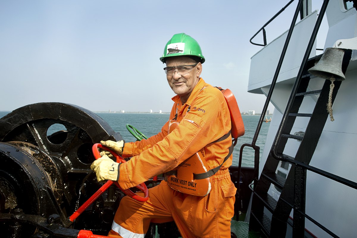 A deckhand in orange overalls at work on a vessel deck