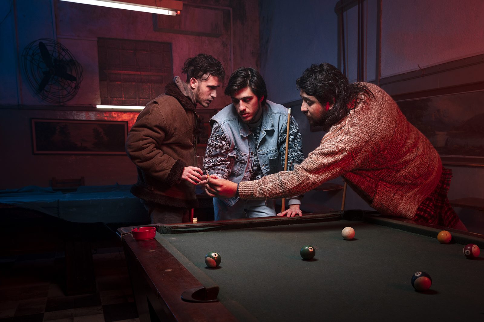 Characters around a pool table in cinematic blue light