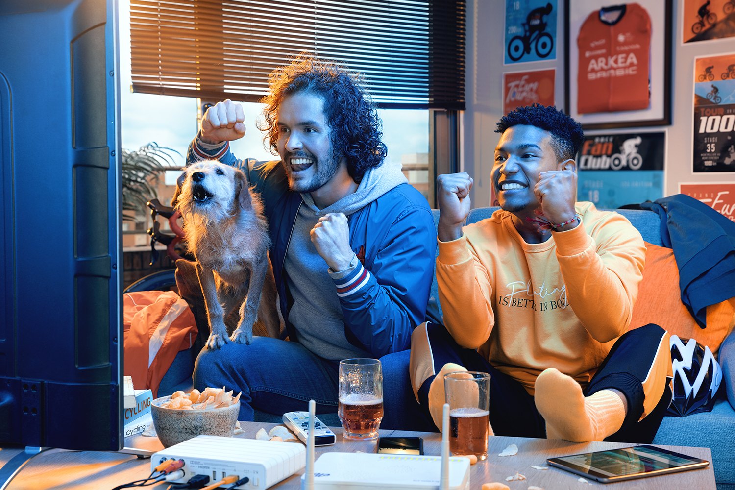Three friends and a dog crowded onto one sofa watching something off frame