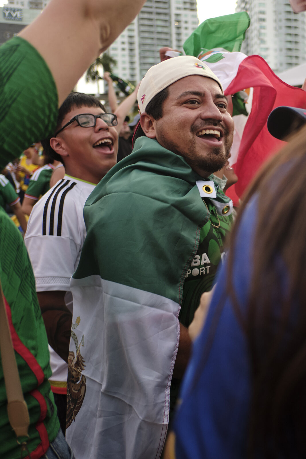 Mexico fans mid-laugh under the flag, green white and red everywhere