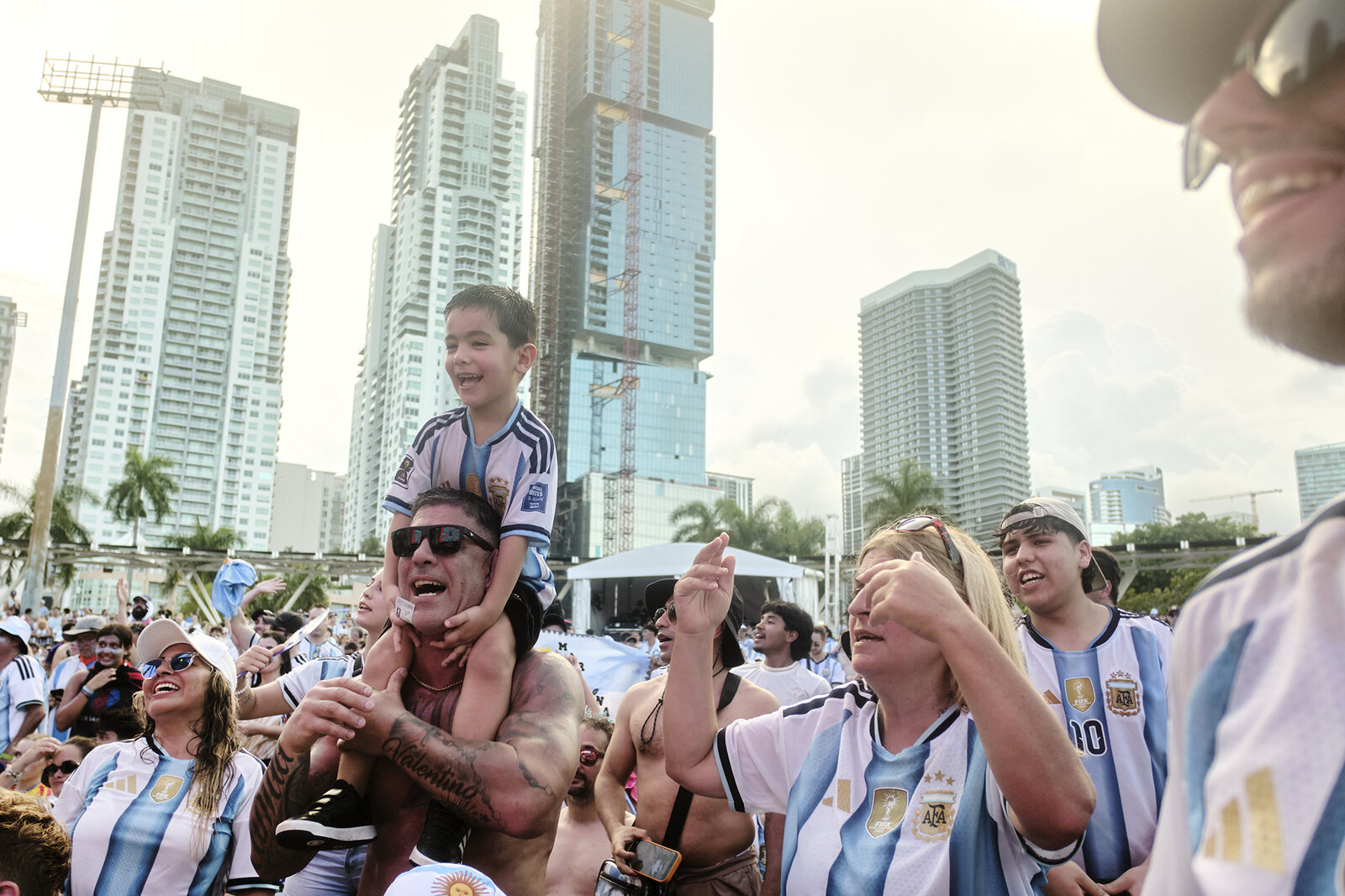 The fan festival crowd roars with the Miami skyline rising behind them