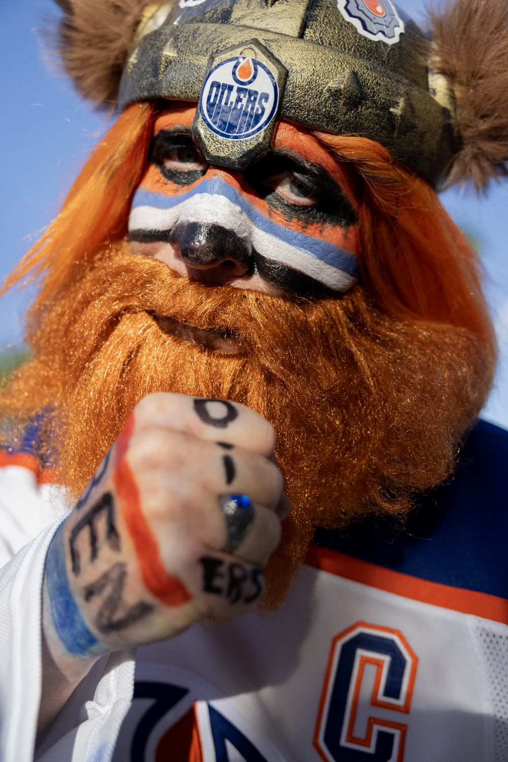 A costumed fan with a painted face and orange beard