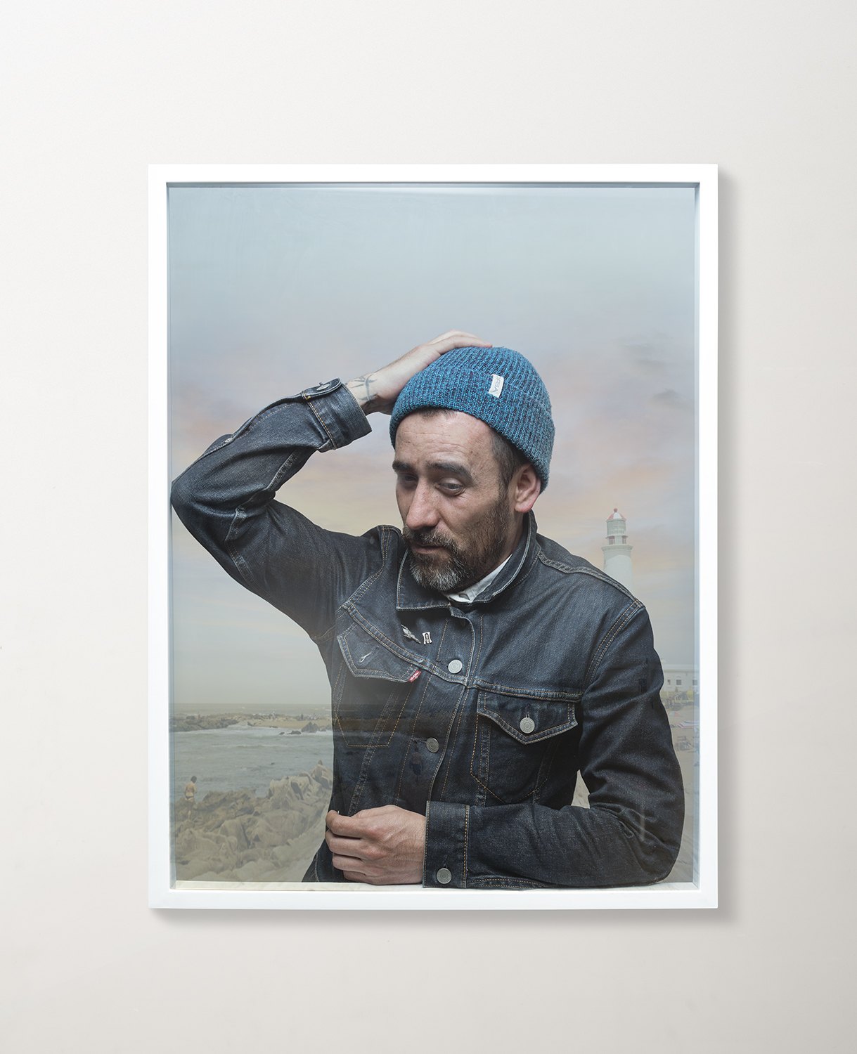 A framed portrait of a man in a denim jacket saluting, hung on a pale wall