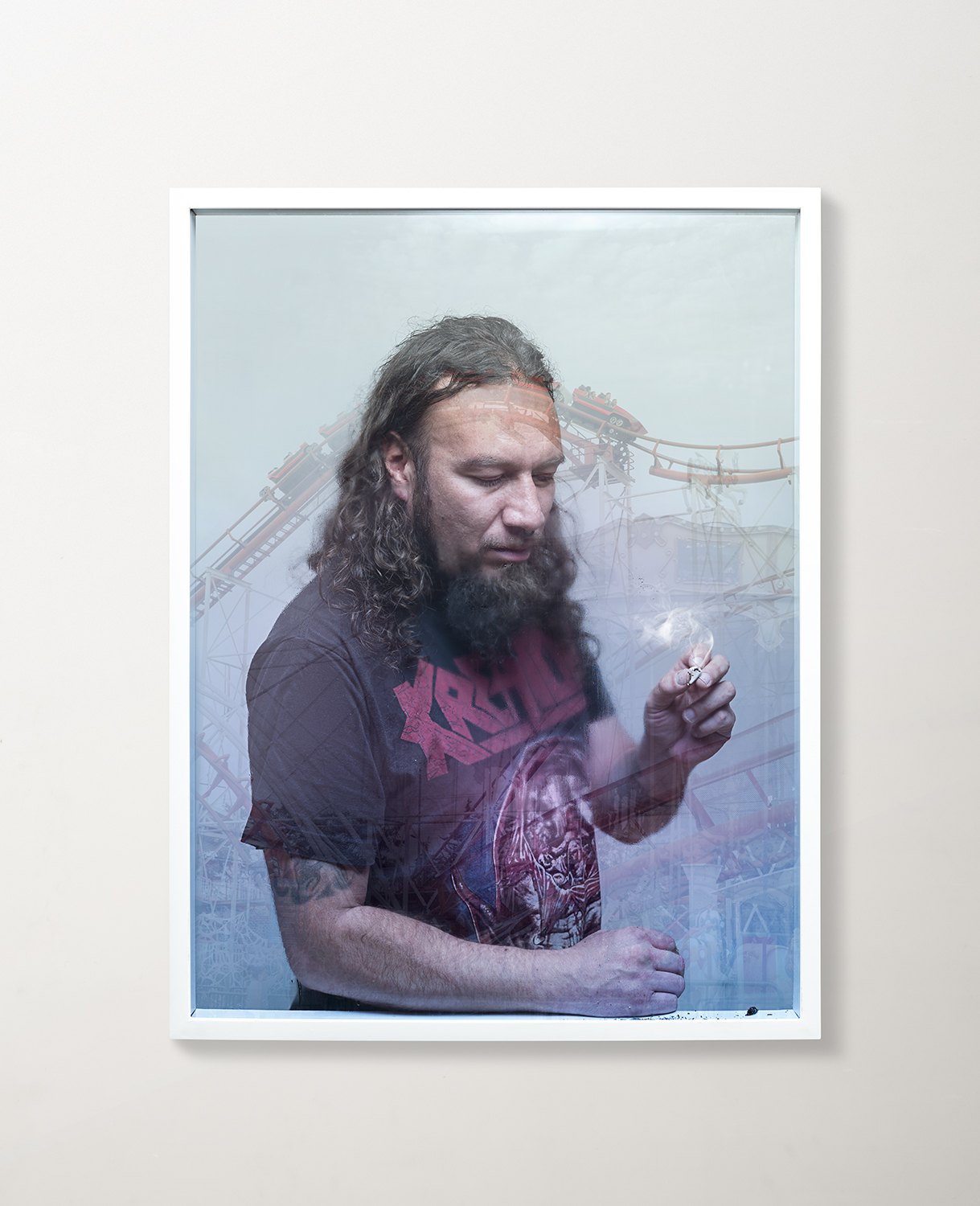 A framed print of a bearded man in a pink shirt against a bright sky