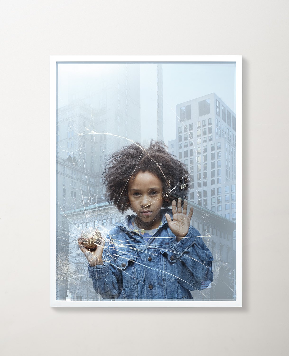 A framed portrait of a child in denim with a city skyline behind her