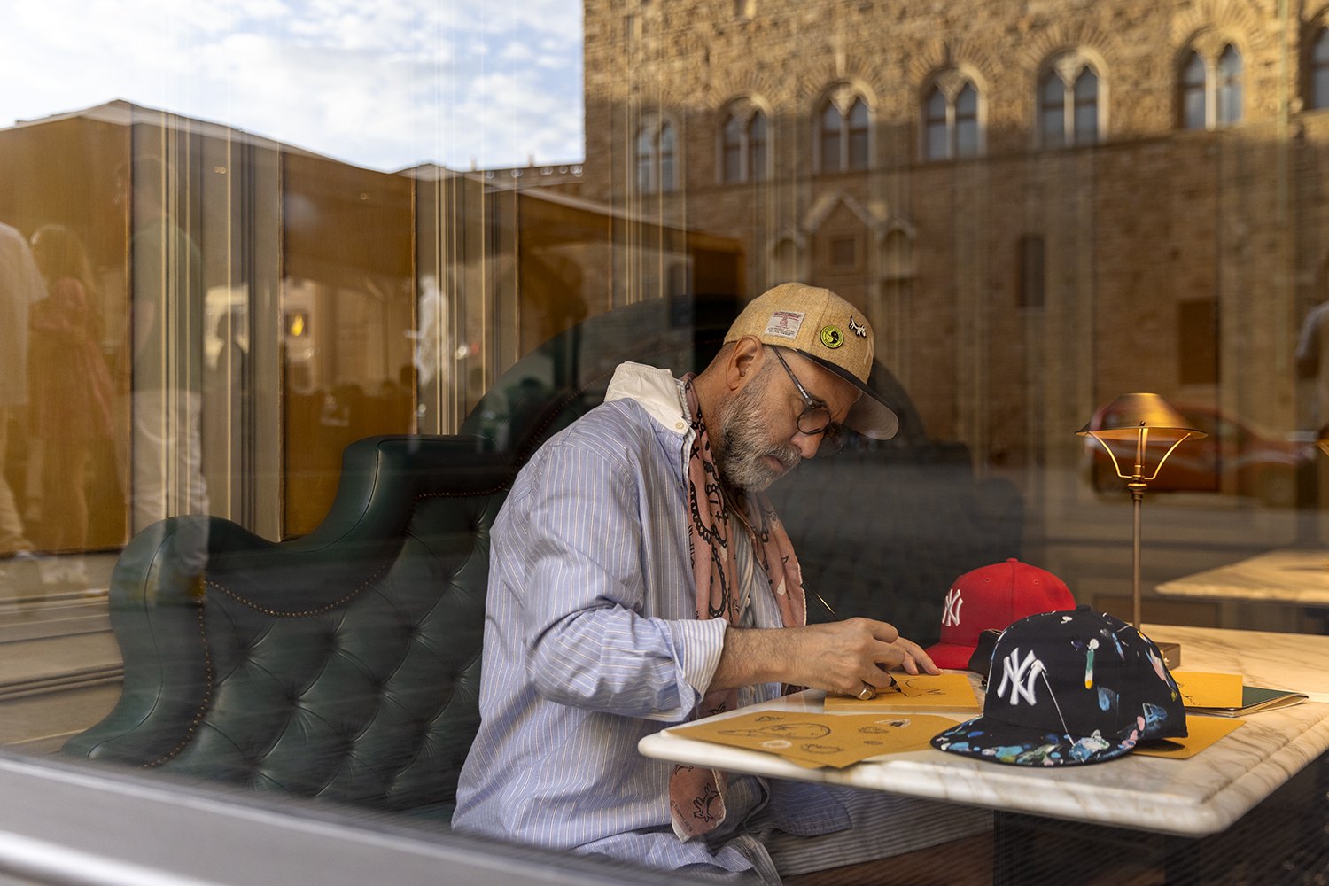 Seen through the window glass, the artist at work with the Piazza della Signoria reflected across him