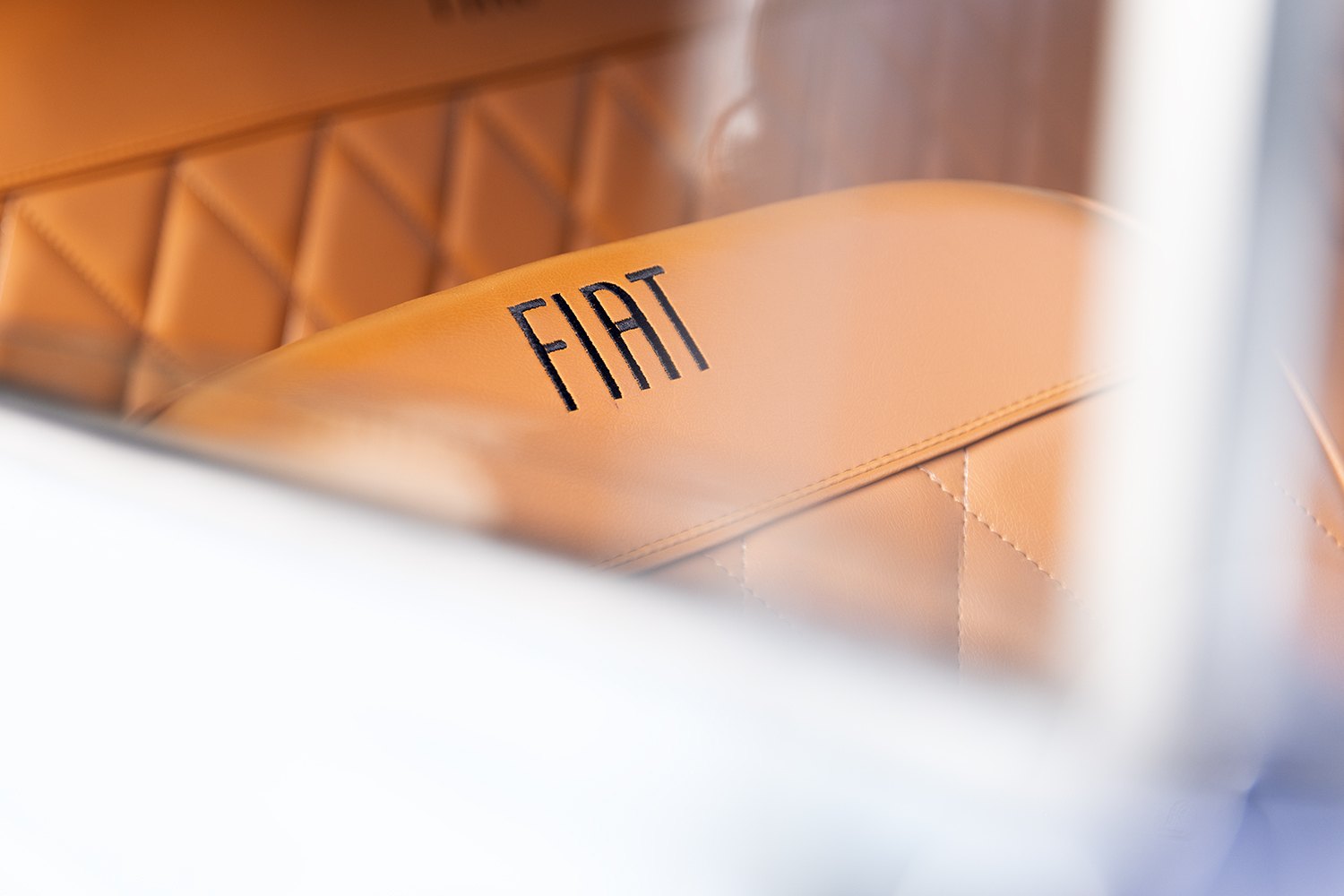 Tan leather interior of the Fiat with the marque stamped into the panel