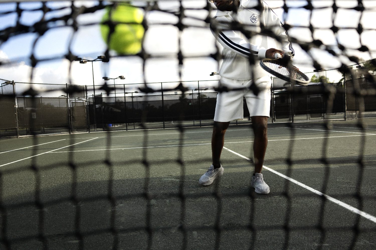 A player in a tracksuit inspects his racket on court