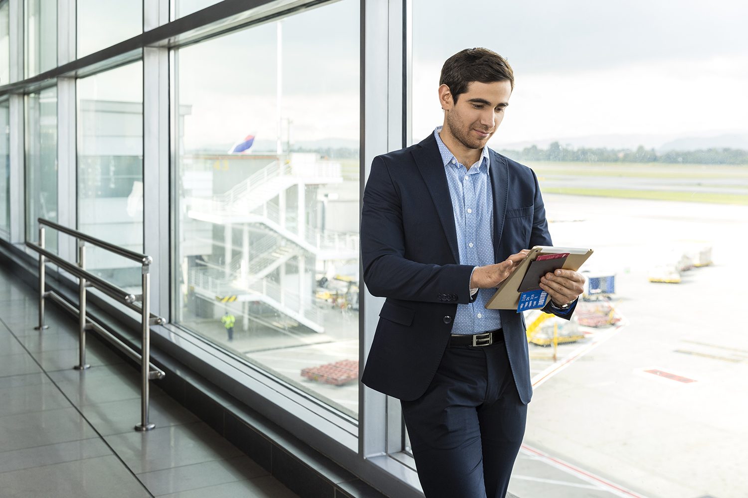 A traveller looks out at the runway with a coffee
