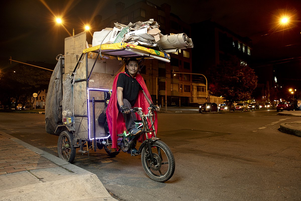 A loaded tricycle cart photographed side-on beneath orange street lighting