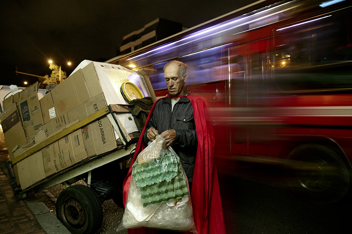 Sorting bagged material beside a cart of stacked appliances, red light trails behind