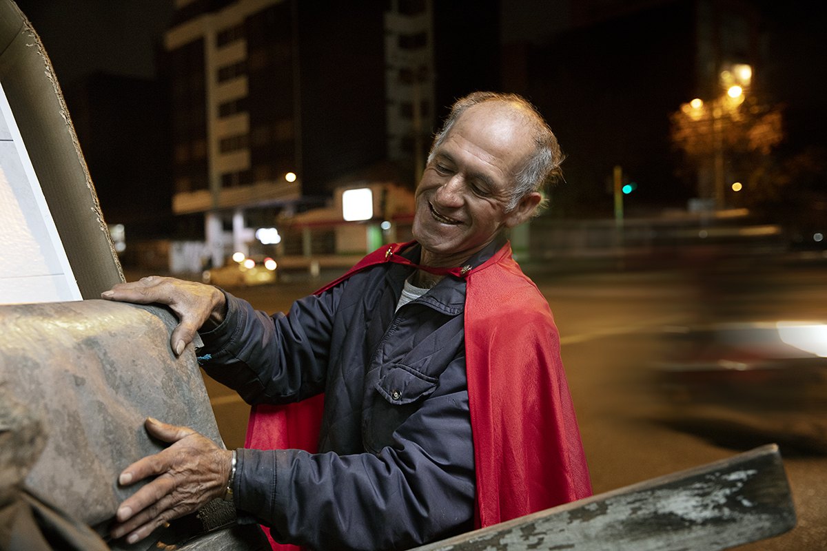A recycler smiling as he pushes his cart along the roadside at night