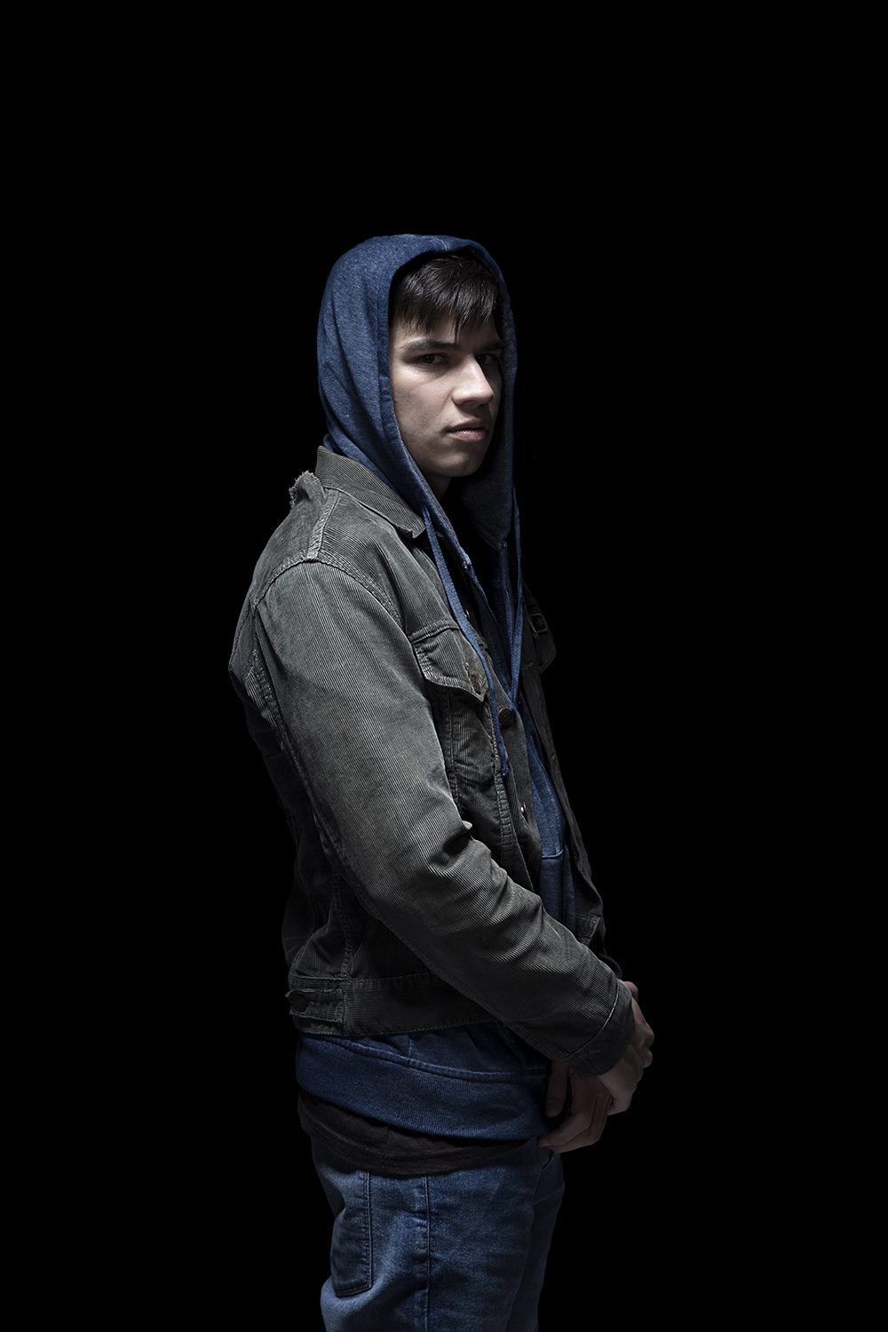 A hooded young character against black