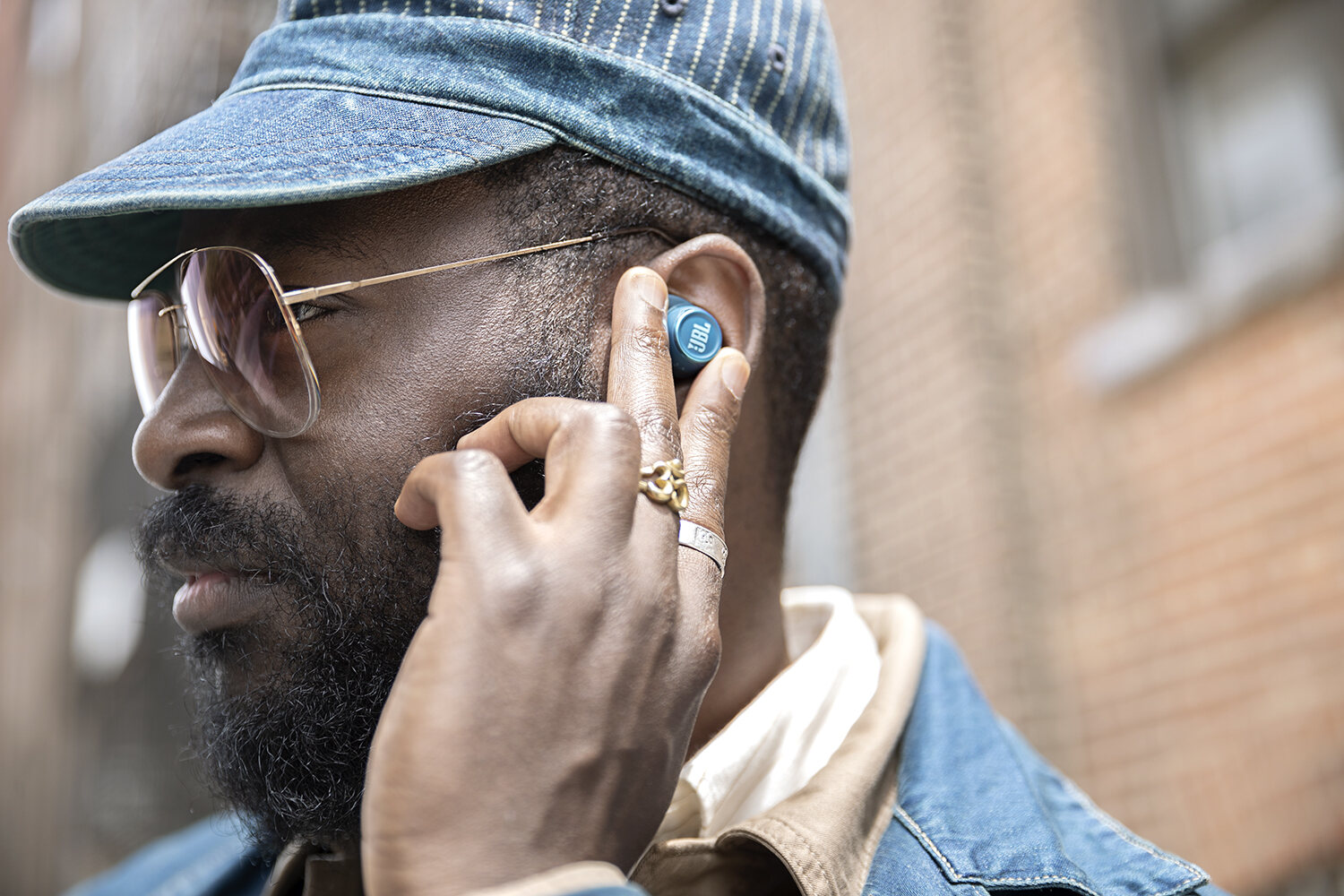 Slipping an earbud in against a red-brick Brooklyn street