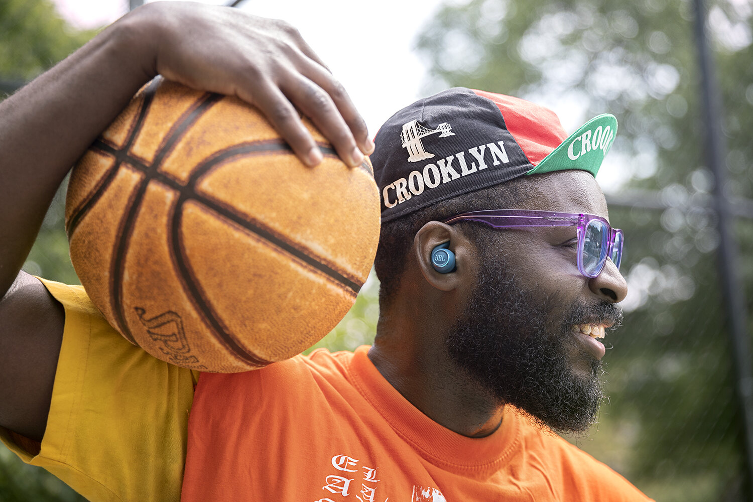 Ball on the shoulder, mid-laugh, earbud still in