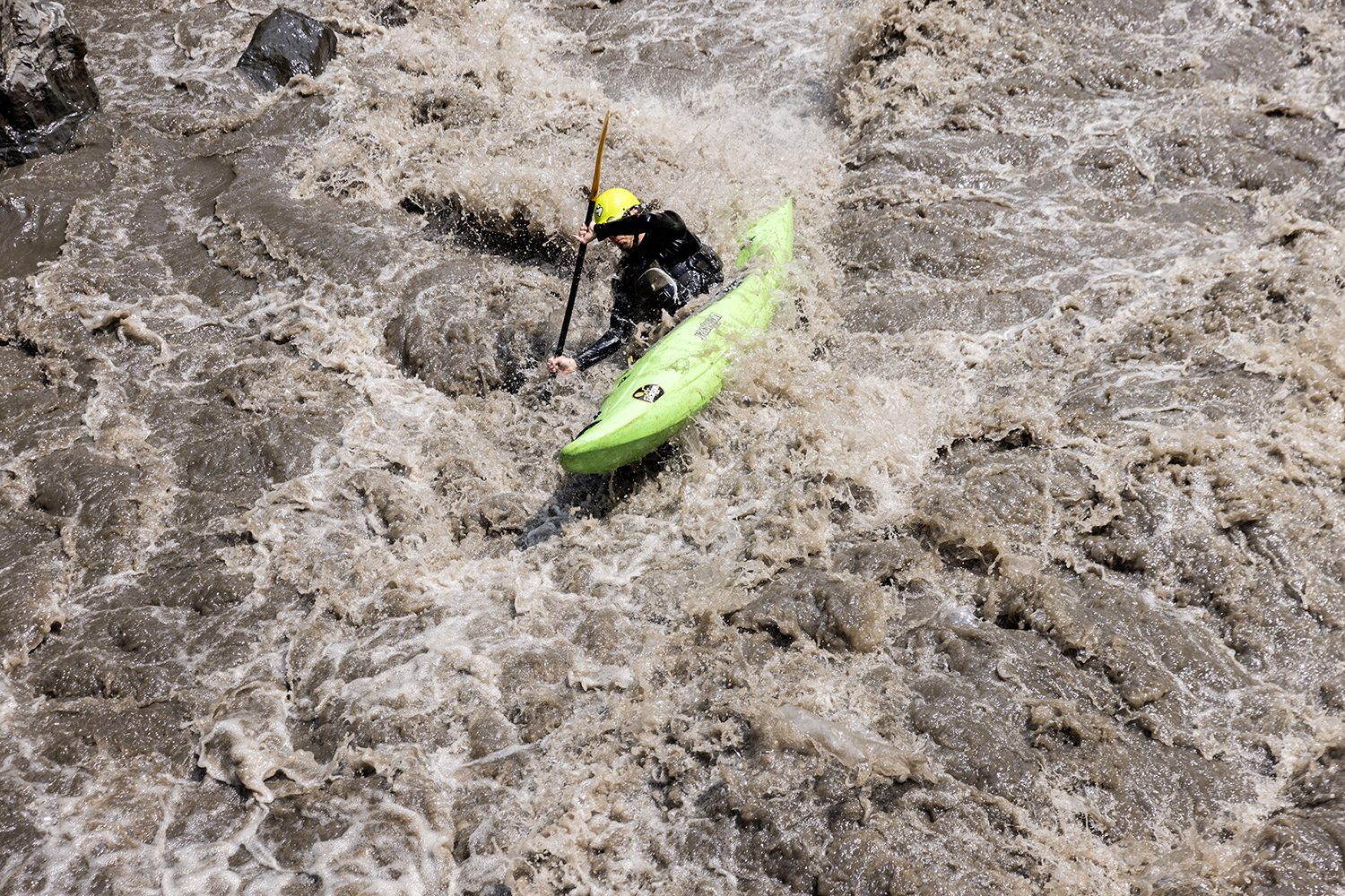 The green kayak drops into churning whitewater