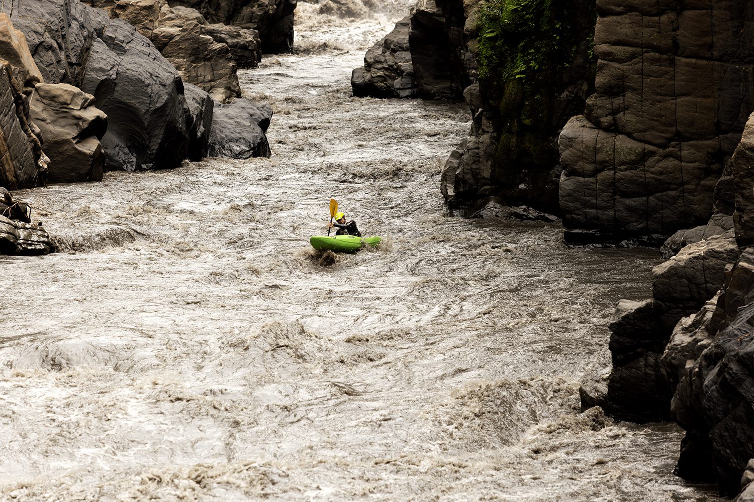 A kayaker threads a canyon between walls of rock