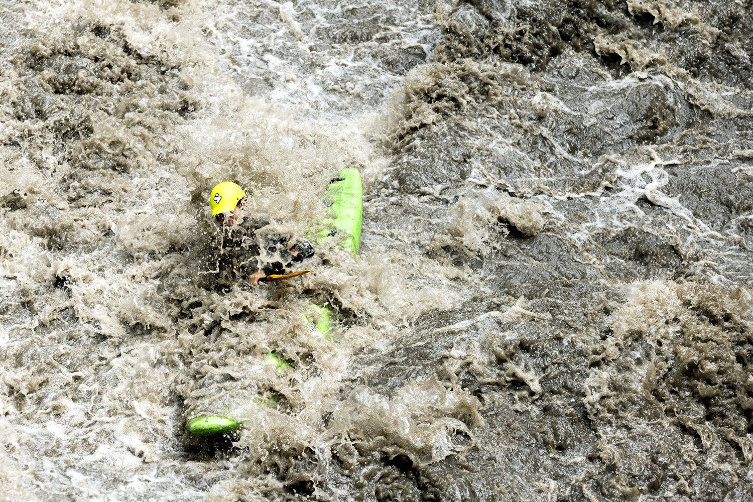 The kayaker punches through a rapid, spray flying