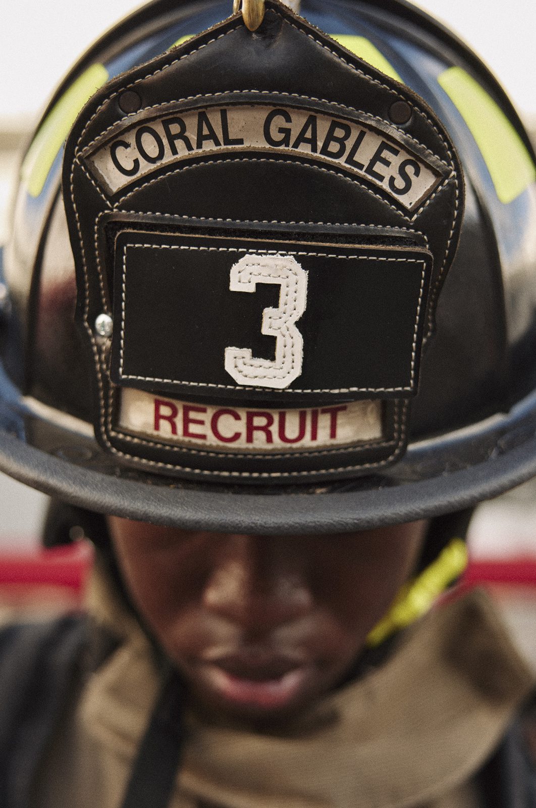 Firefighter in helmet looks toward the light, badge number visible