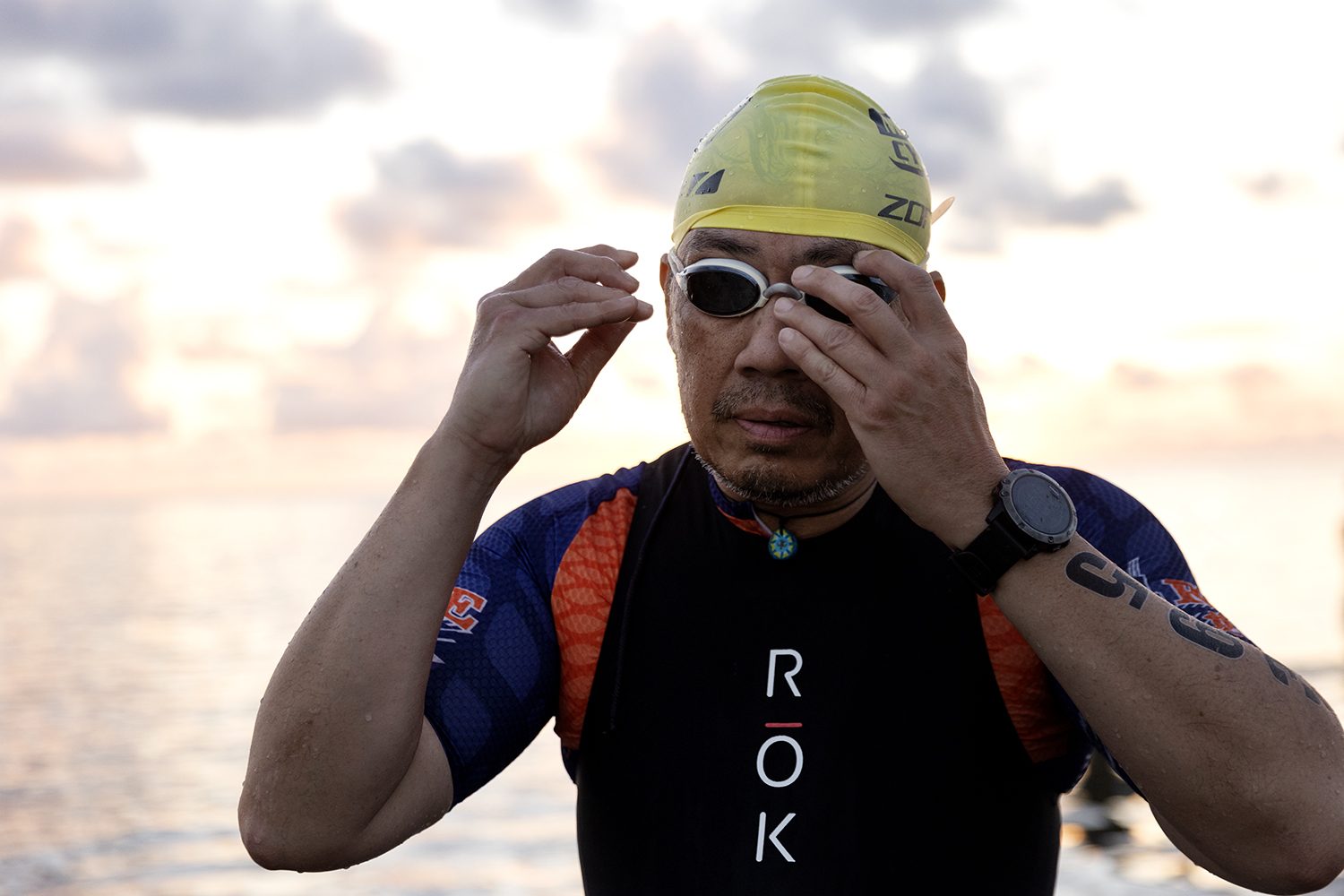 An athlete adjusts goggles before the dawn swim
