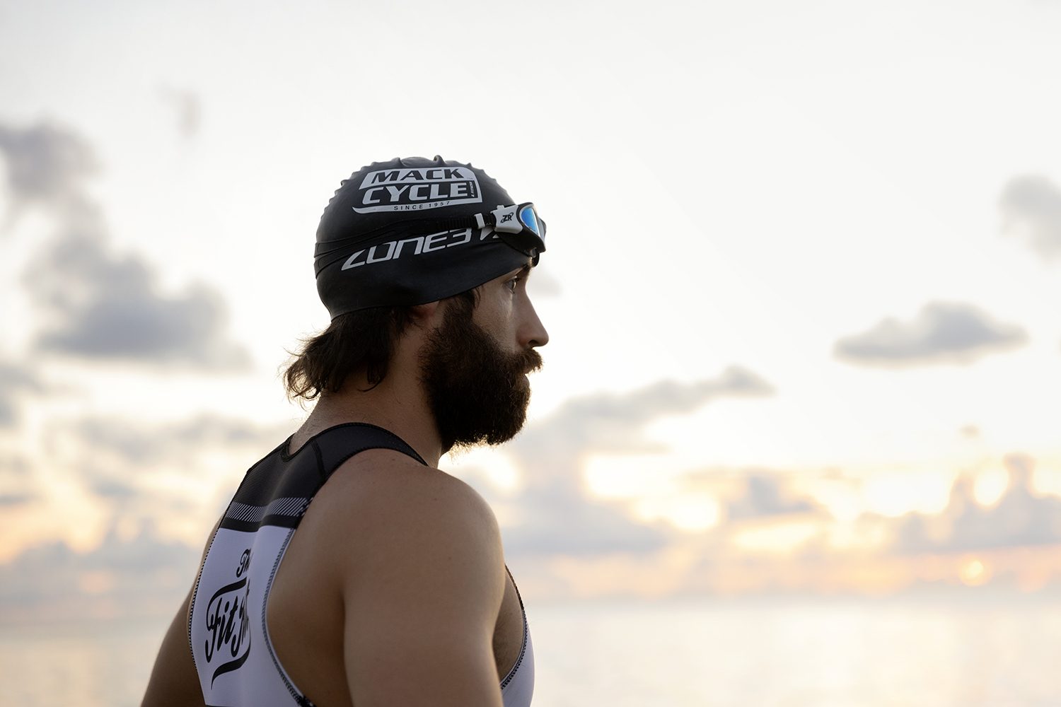 Profile of a swimmer in a cap and goggles at dawn